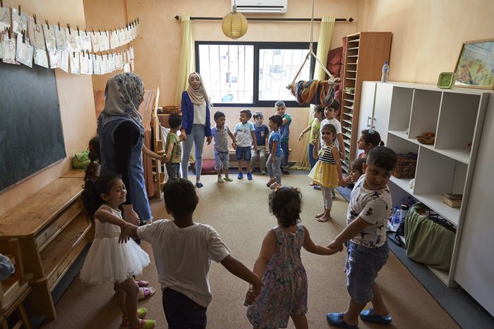 Eine Kindergartengruppe mit Erzieherinnen steht Hand in Hand im Kreis. (Quelle: Ulrich Gernhardt)