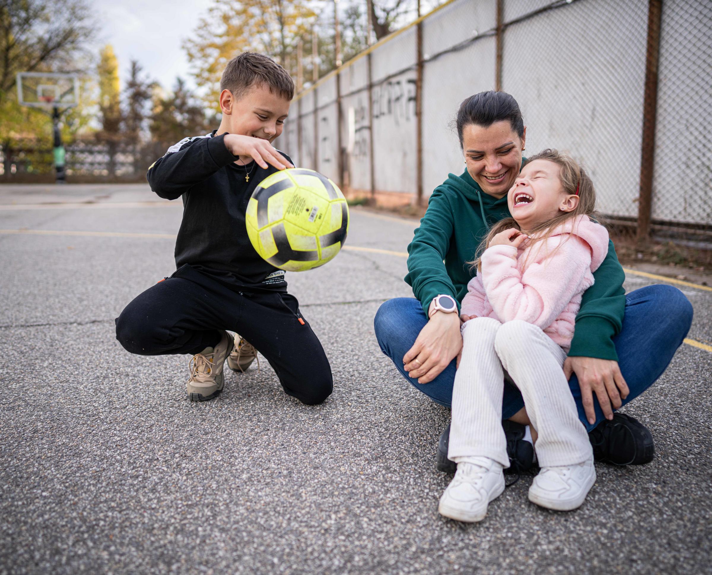 Junge mit einem Fußball neben seiner Mutter und seiner Schwester (Foto: Jakob Studnar / Kindernothilfe)