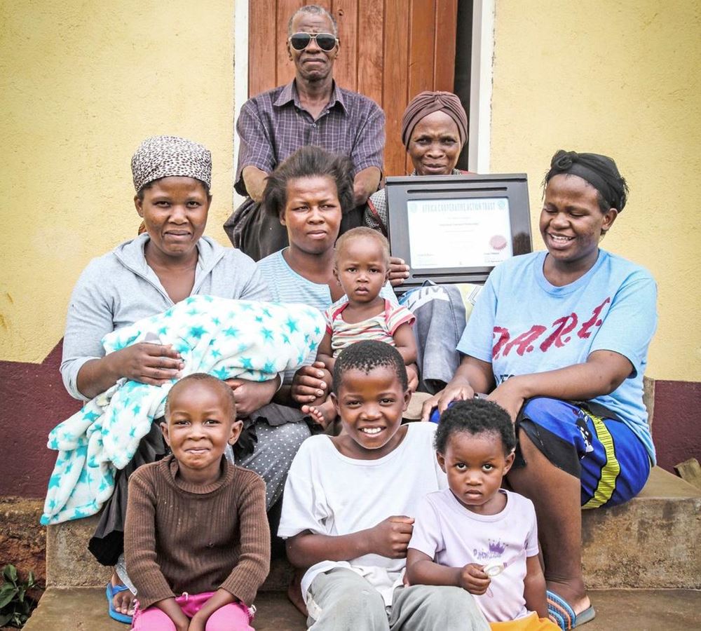 Reportage: "Eswatini: Eine Frau startet erfolgreich durch" Foto einer Familie vor Hauseingang (Quelle: Ralf Krämer, Kindernothilfe)