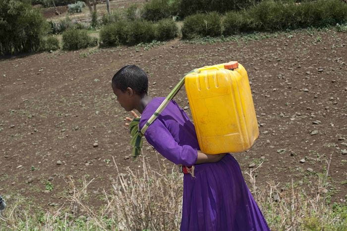 Ein äthiopisches Mädchen schleppt einen schweren Wasserkanister auf ihrem Rücken: (Quelle: Frank Rothe)