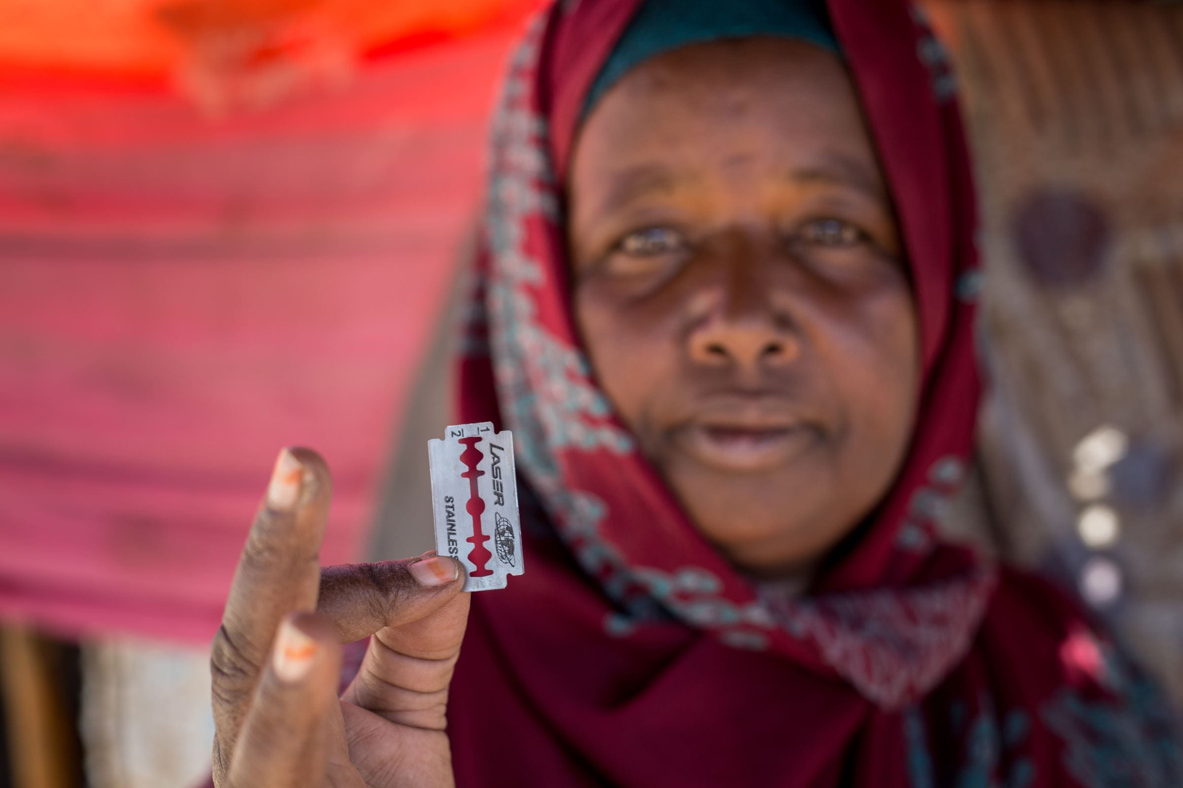 Die ehemalige Beschneiderin Khadra aus Somaliland hält eine Rasierklinge in die Kamera. (Quelle: Mustafa Saeed/Kindernothilfe)