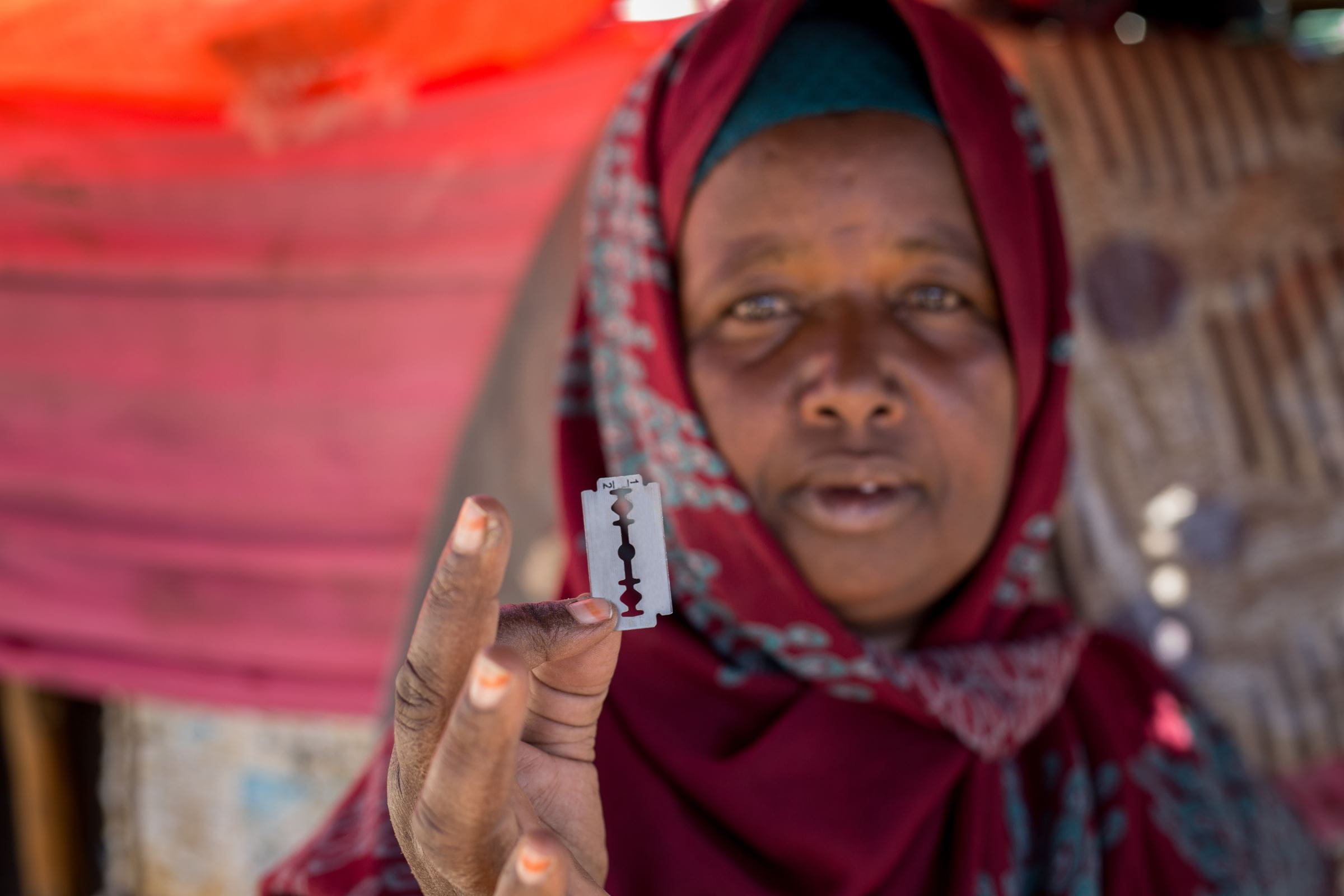 Eine ehemalige Beschneiderin aus Somaliland hält eine Rasierklinge in die Kamera (Quelle: Fairpicture)