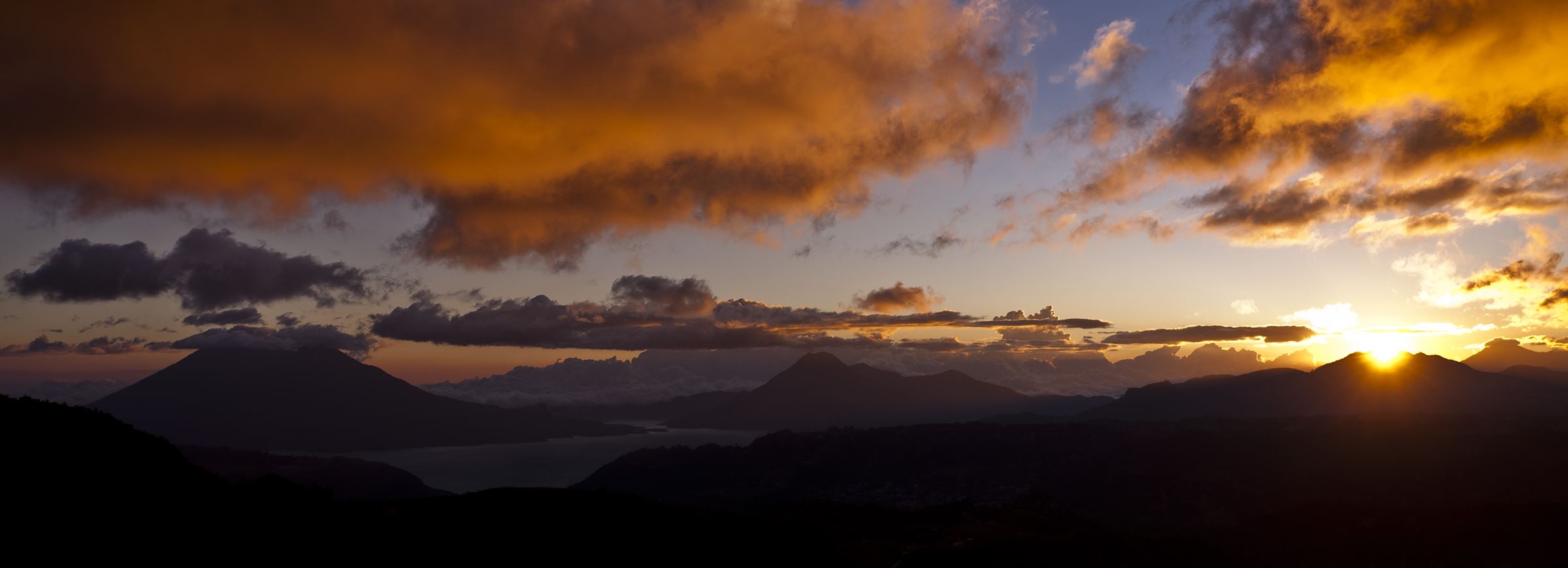 Dunkle Berglandschaft, Abendhimmel, rechts leuchtet die Sonne hervor (Quelle: Jakob Studnar)