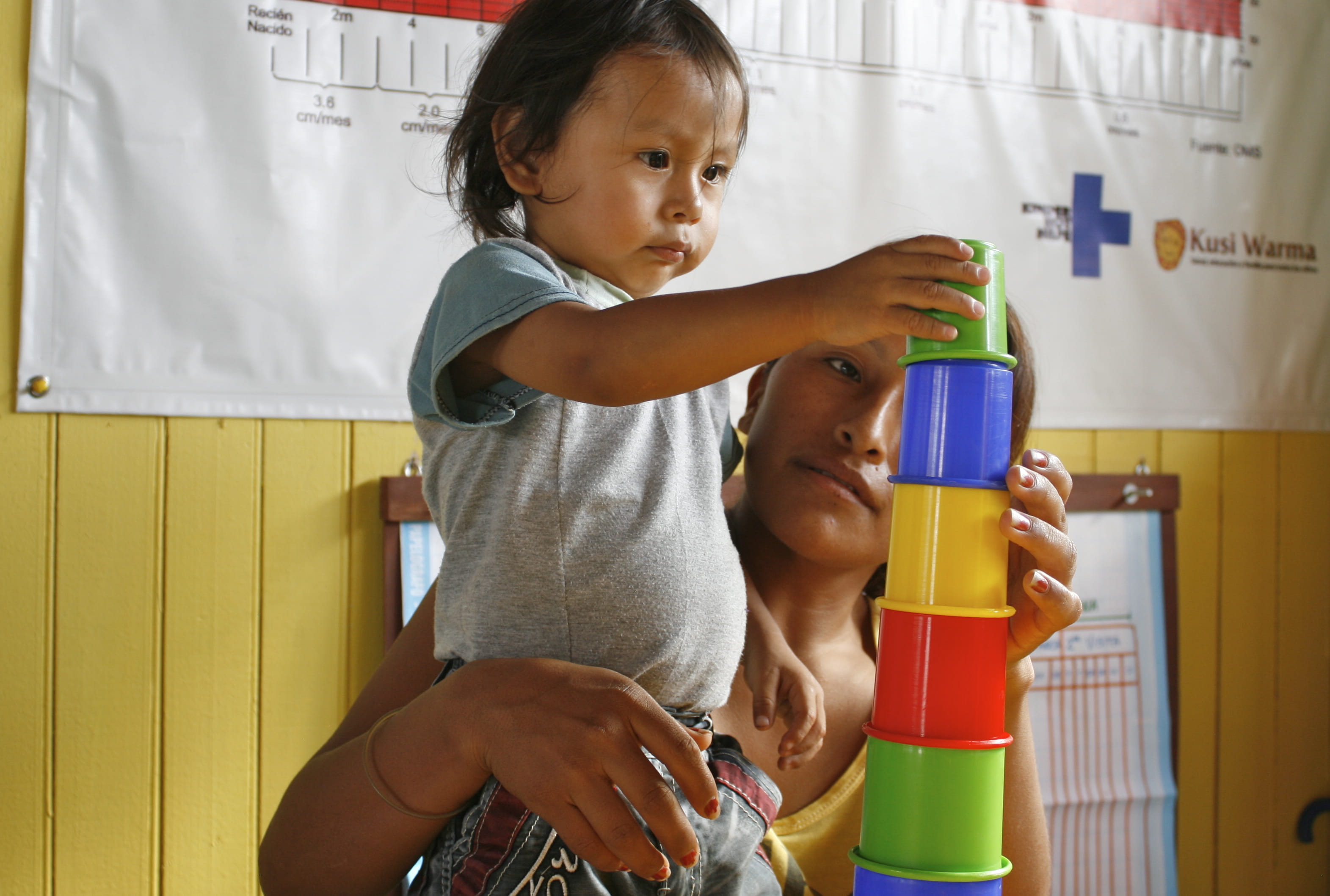 Kind stapelt Becher in einem Kinderzentrum in Lima, Peru. 