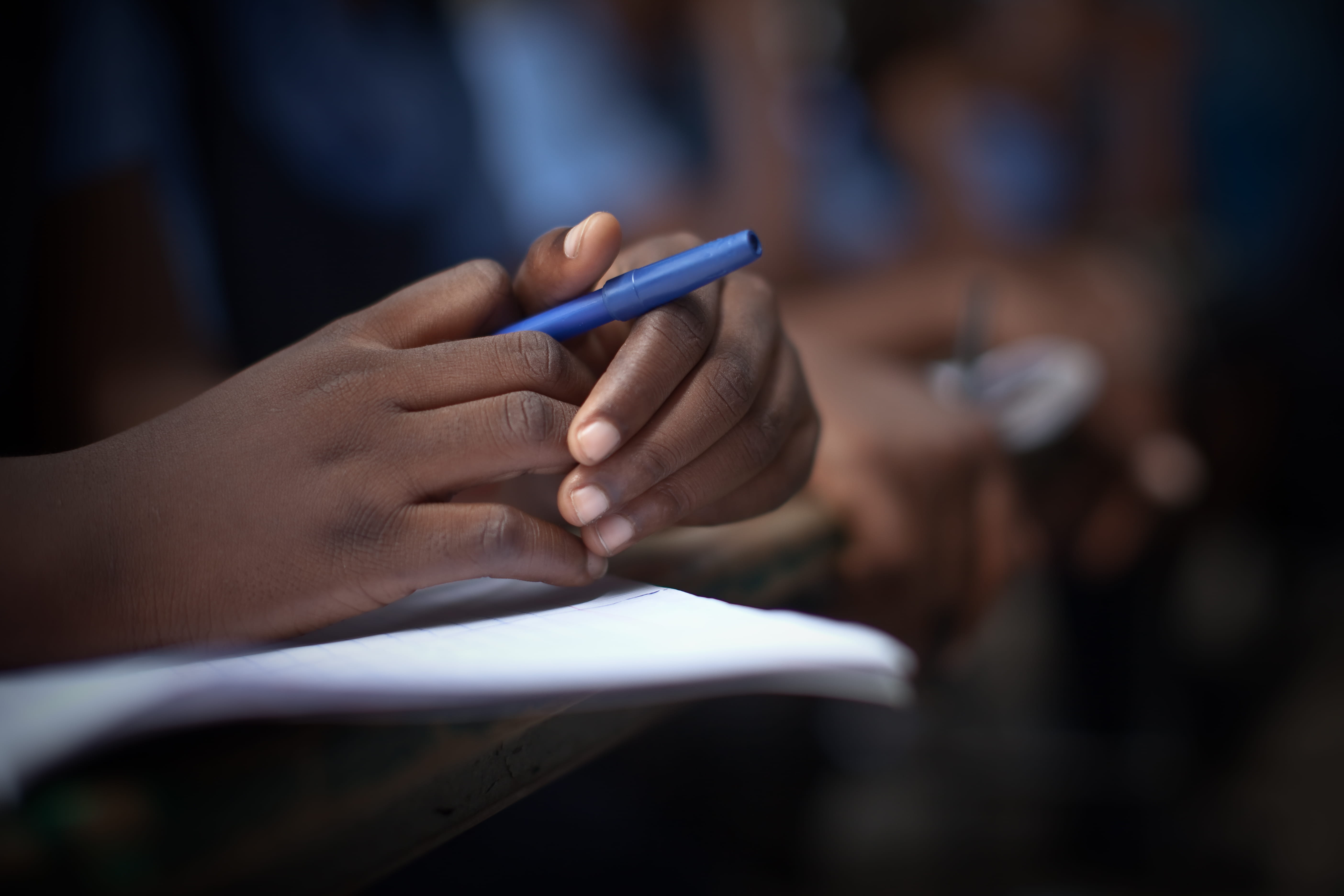 Kinderhand hält einen blauen Stift