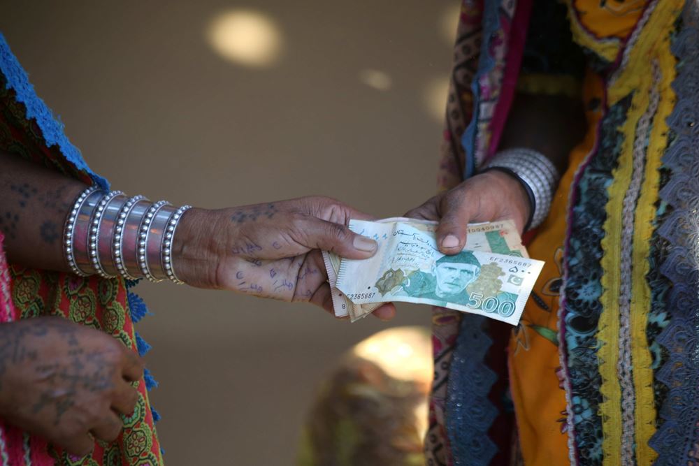 Eine Frau reicht einer anderen Geldscheinein die Hand. (Quelle: Kindernothilfepartner)