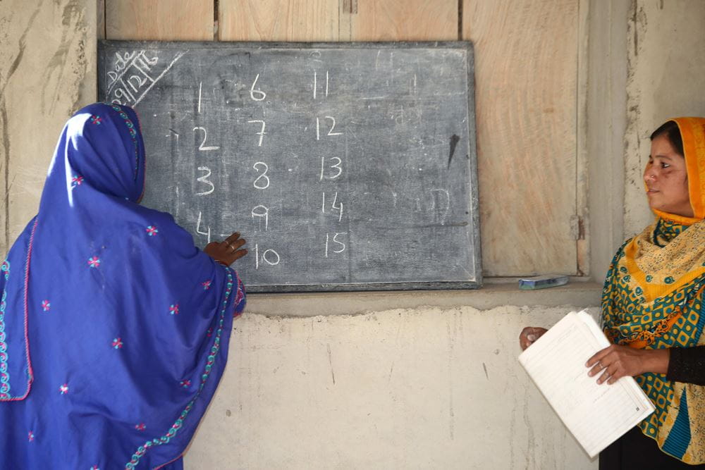 Zwei Frauen stehen an einer Tafel, auf der Zahlen geschrieben sind. (Quelle: Kindernothilfepartner)