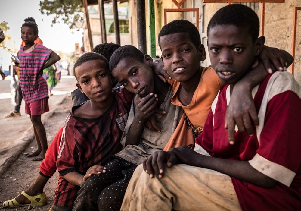 Vier Jungen aus Äthiopien sitzen am Straßenrand und schauen in die Kamera. (Quelle: Jakob Studnar)