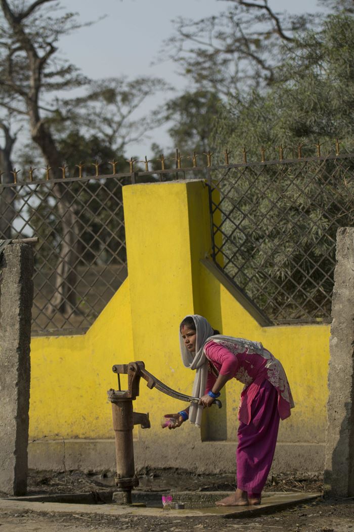 Eine Frau aus Nepal steht an einer Wasserpumpe und holt Wasser. (Quelle: Christian Nusch)