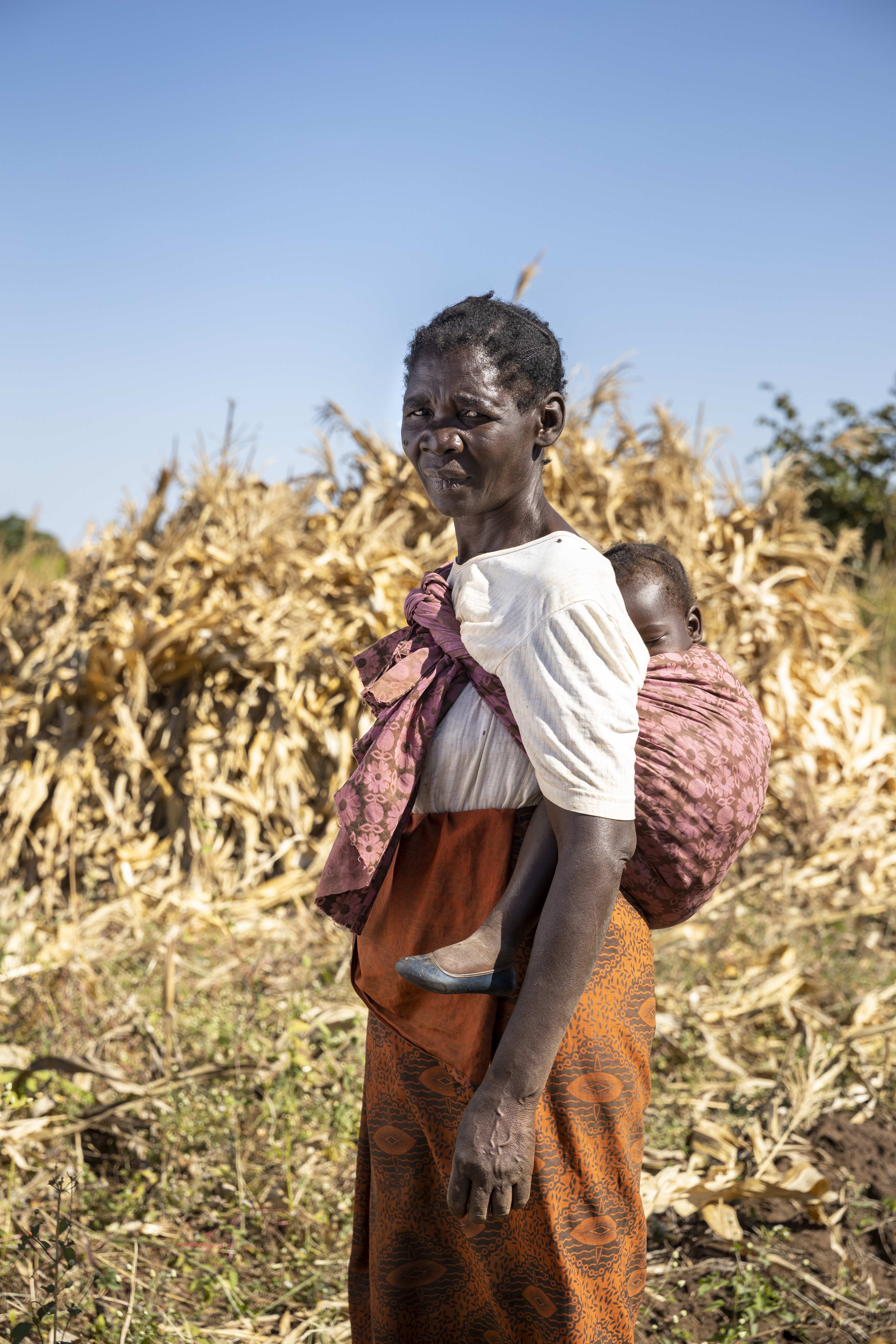 Eine Frau aus Sambia mit einem Kind auf dem Rücken.