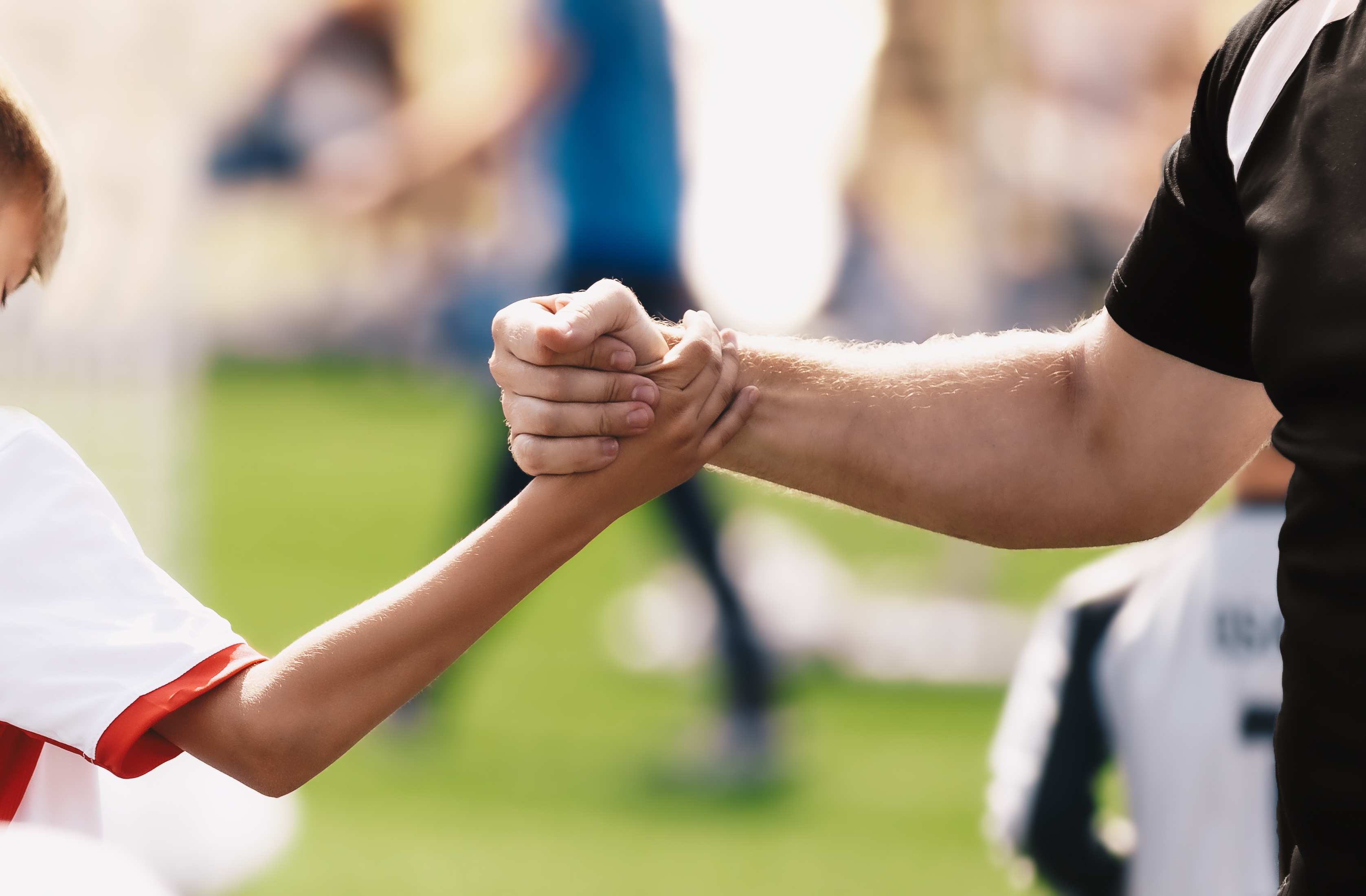 	Trainer und junger Spieler machen "Shake hands" (Quelle: Adobe Stock)