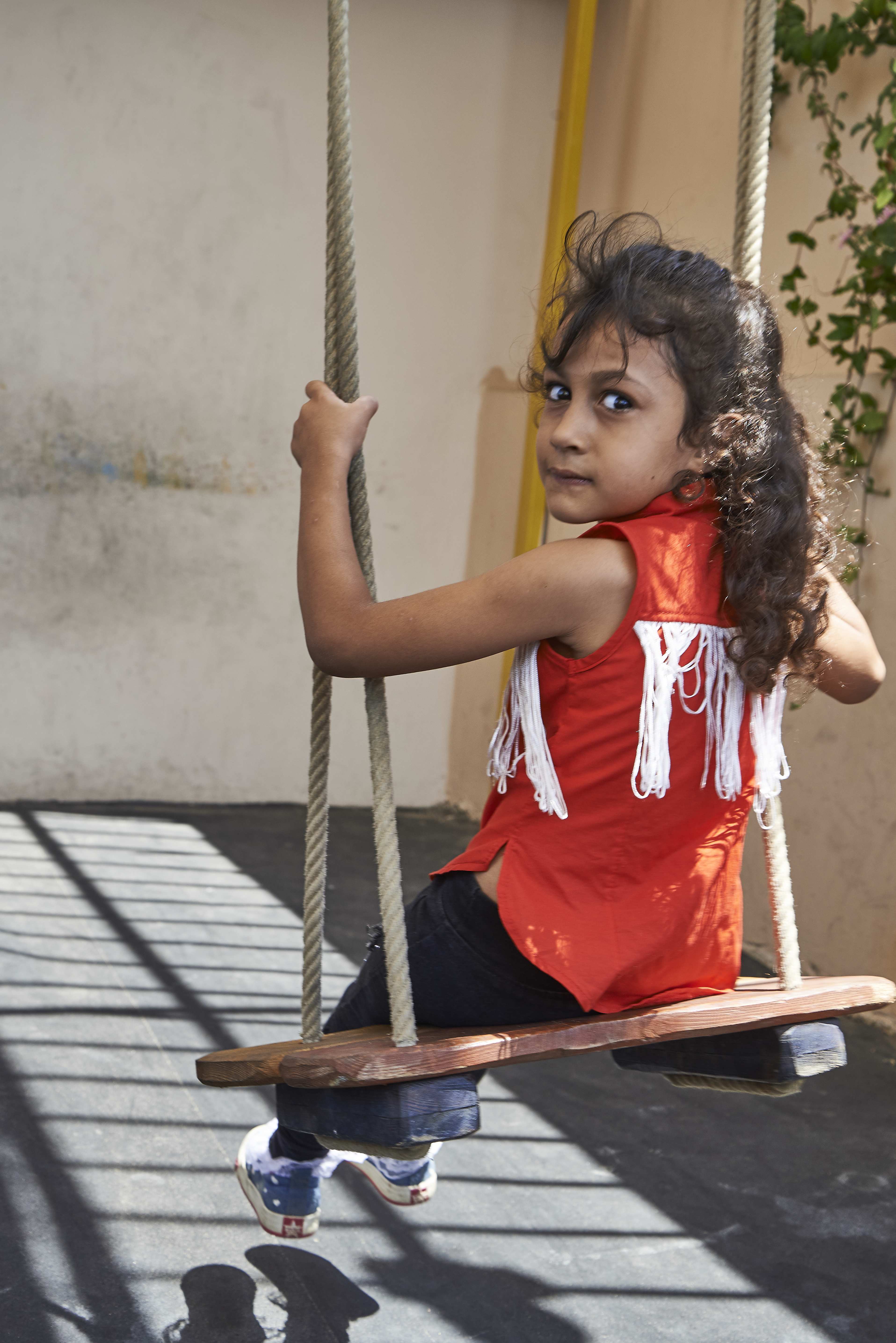 Ein Mädchen sitzt auf einer Schaukel und blickt über ihre Schulter. (Quelle: Ulrich Gernhardt)