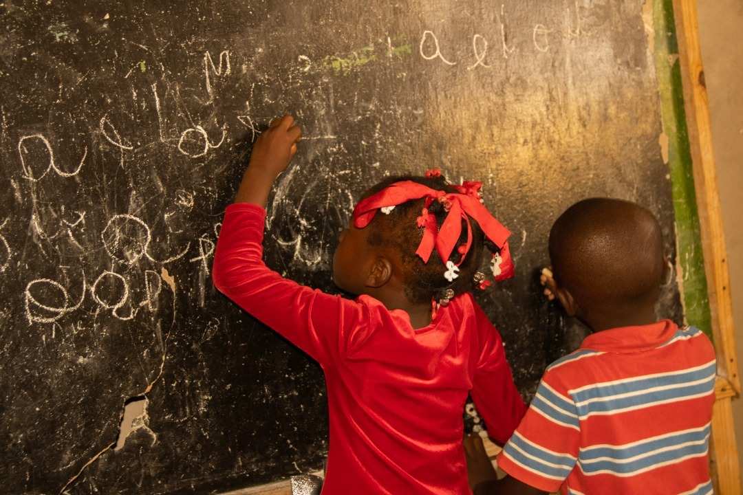 Kinder schreiben an eine Tafel in einer Schule in Haiti Quelle: Kindernothilfe Partner