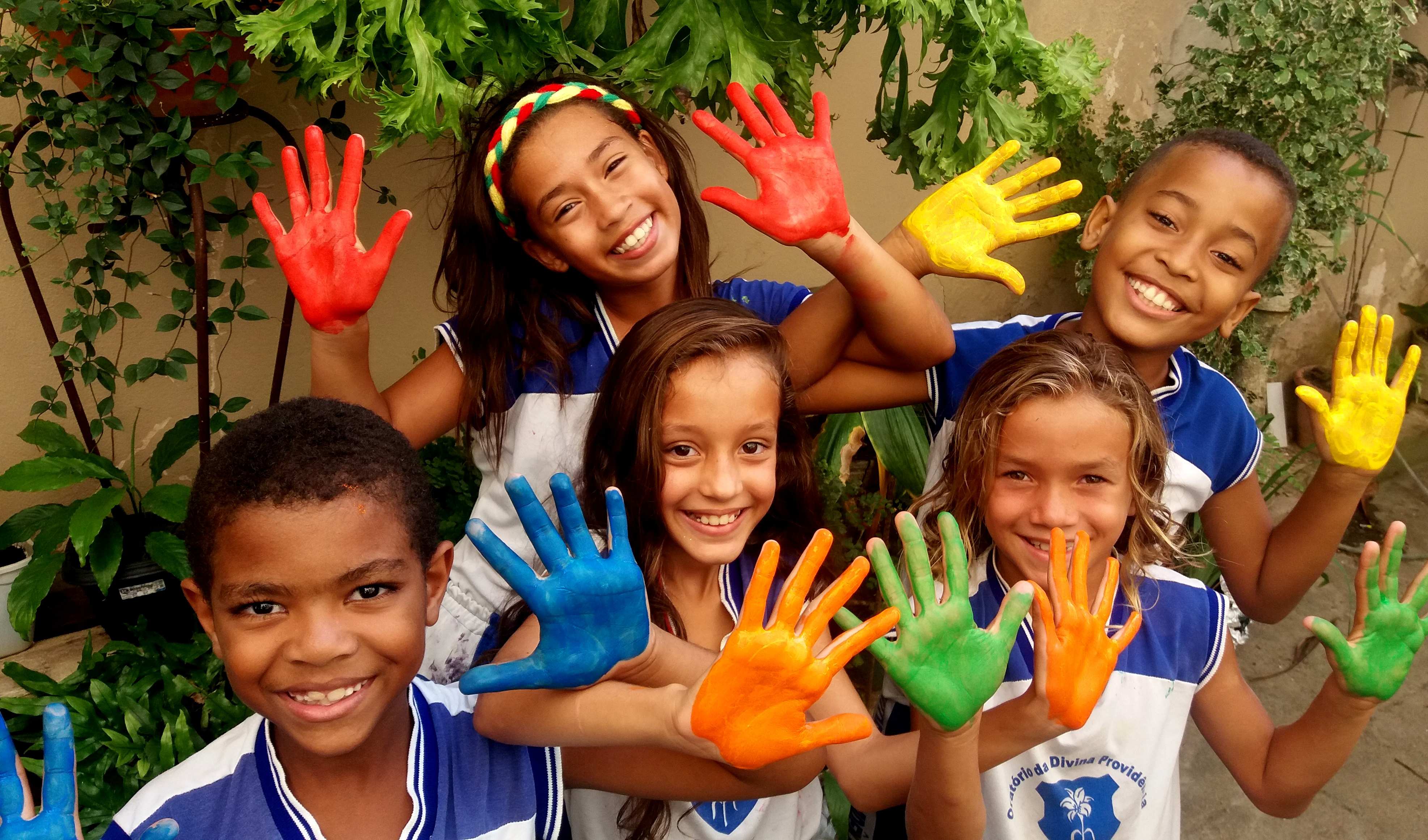 Mädchen und Jungen lächeln und strecken ihre bunt bemalten Hände  Mädchen und Jungen lächeln und strecken ihre bunt bemalten Hände