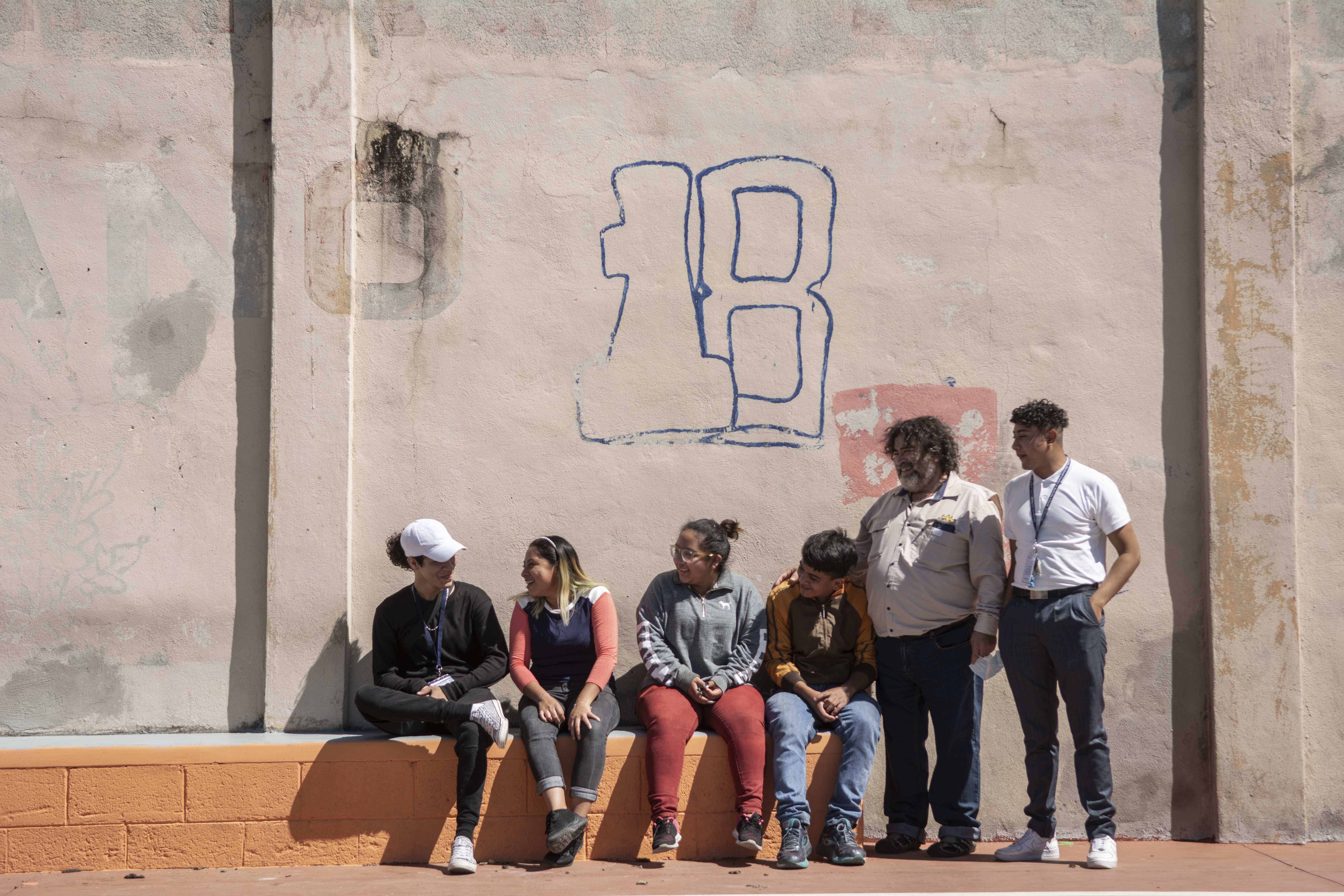 Jugendliche sitzen vor einer Wand mit einer gemalten 18 (Quelle: Christian Nusch)