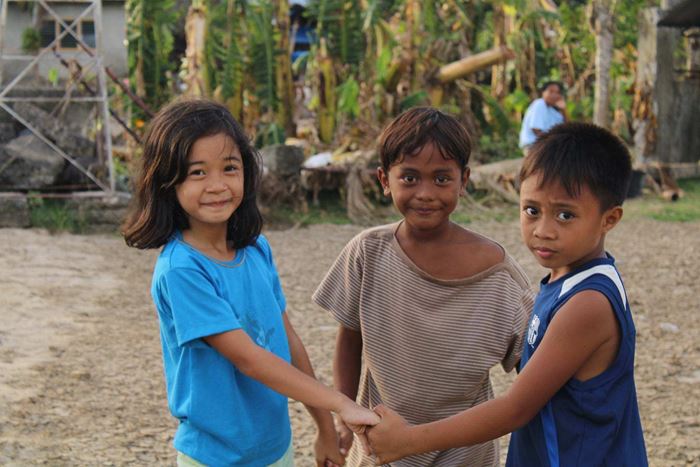 Drei Kinder auf Negros Island spielen im Chaos nach Taifun Rai. (Quelle: Kindernothilfe-Partner CFIM)