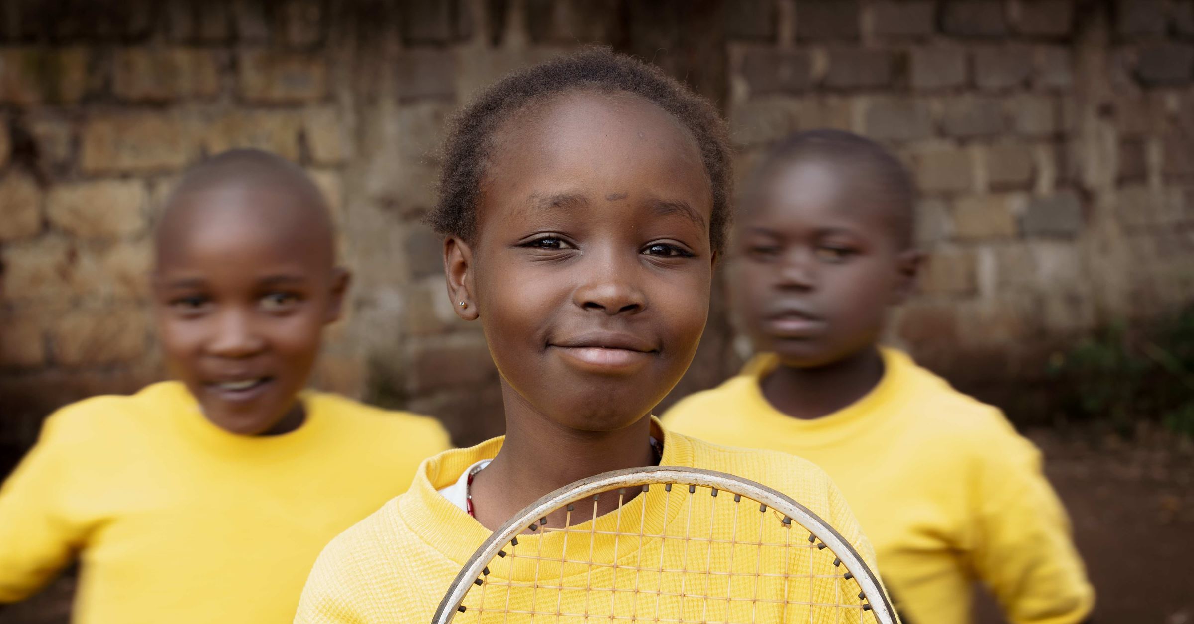 Ein Mädchen aus Kenia im gelben T-Shirt mit Tennisschläger. (Quelle: Lars Heidrich)