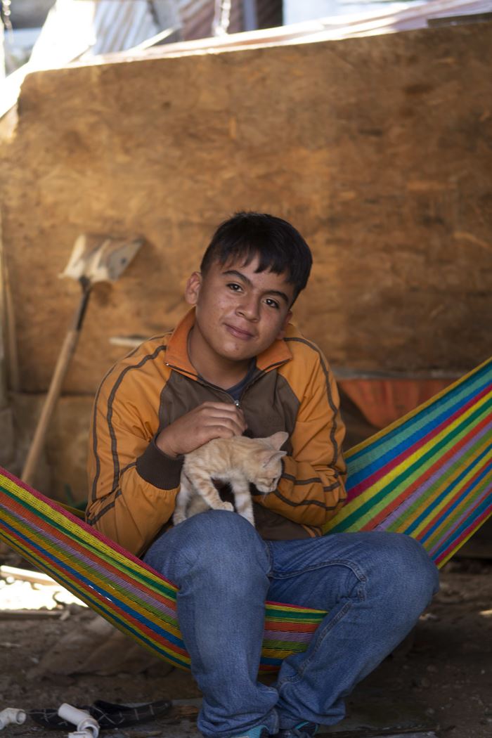 Javier aus Guatemala sitzt mit einer Katze auf dem Schoß in einer Hängematte im Jugendzentrum, in dem er jeden Tag verbringt (Quelle: Christian Nusch)