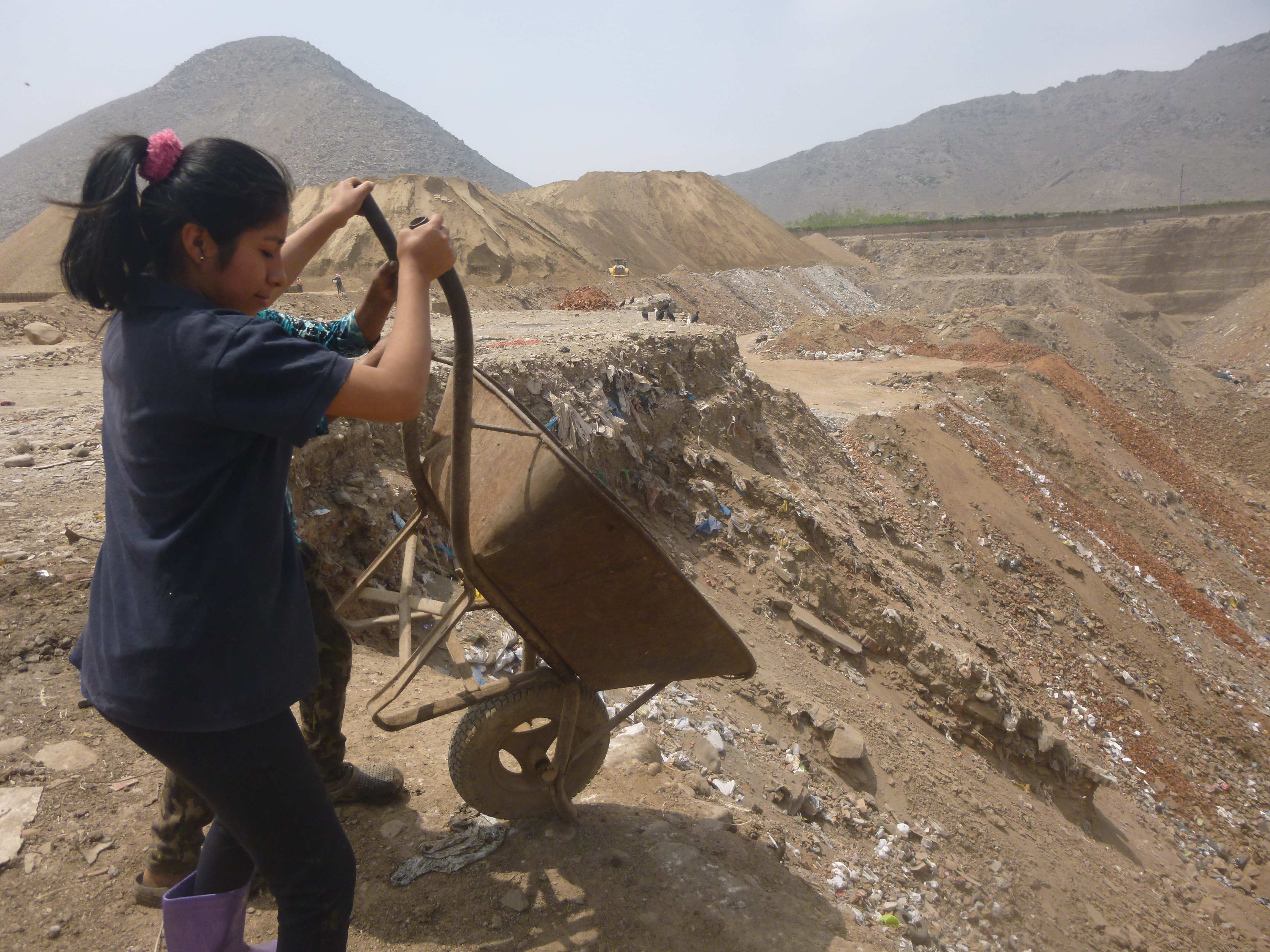 Ein Mädchen in Peru kippt Sand aus einer Schubkarre (Copyright KNH)