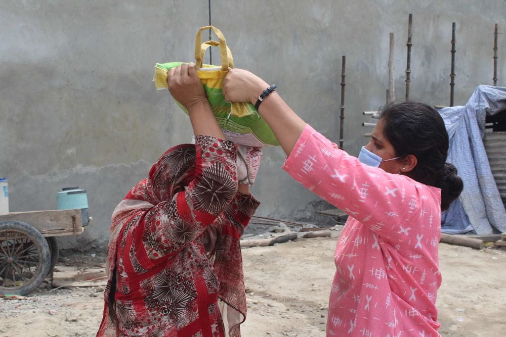 Eine Projektmitarbeiterin aus Indien verteilt Nahrungsmittel an eine Frau während der Corona-Pandemie. (Quelle: Kindernothilfe-Partner)