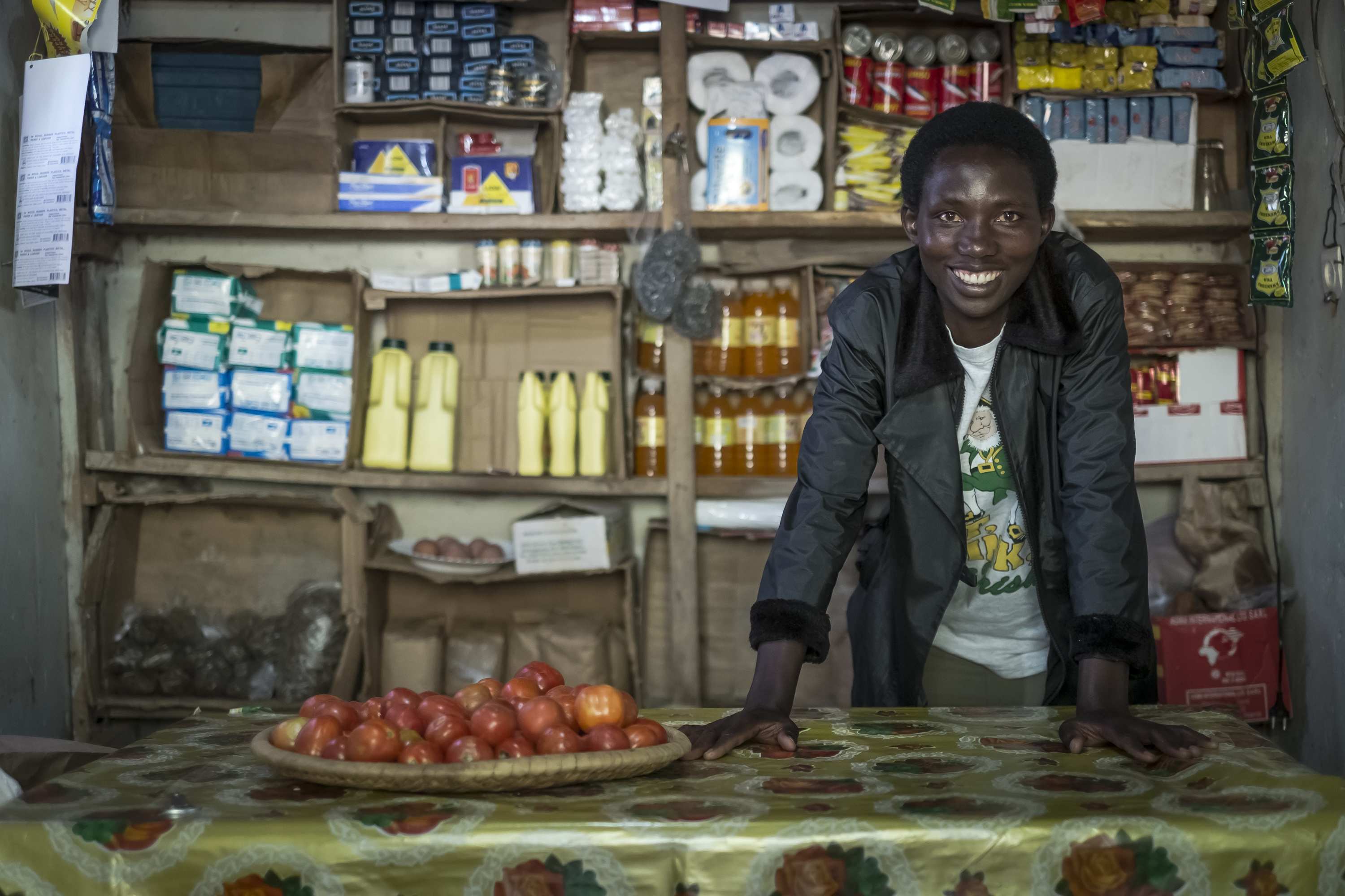 Eine Frau aus Ruanda steht strahlend in ihrem kleinen Laden. (Quelle: Jakob Studnar)