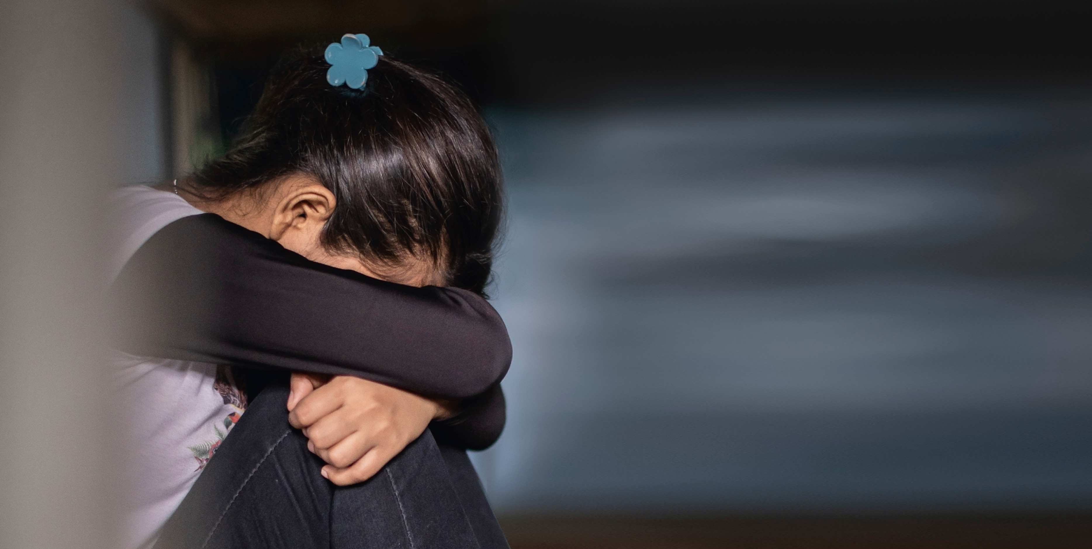 Ein verängstigtes Mädchen verschränkt die Arme und versteckt sein Gesicht, Symbolbild zum Thema Gewalt, Foto: Kindernothilfe