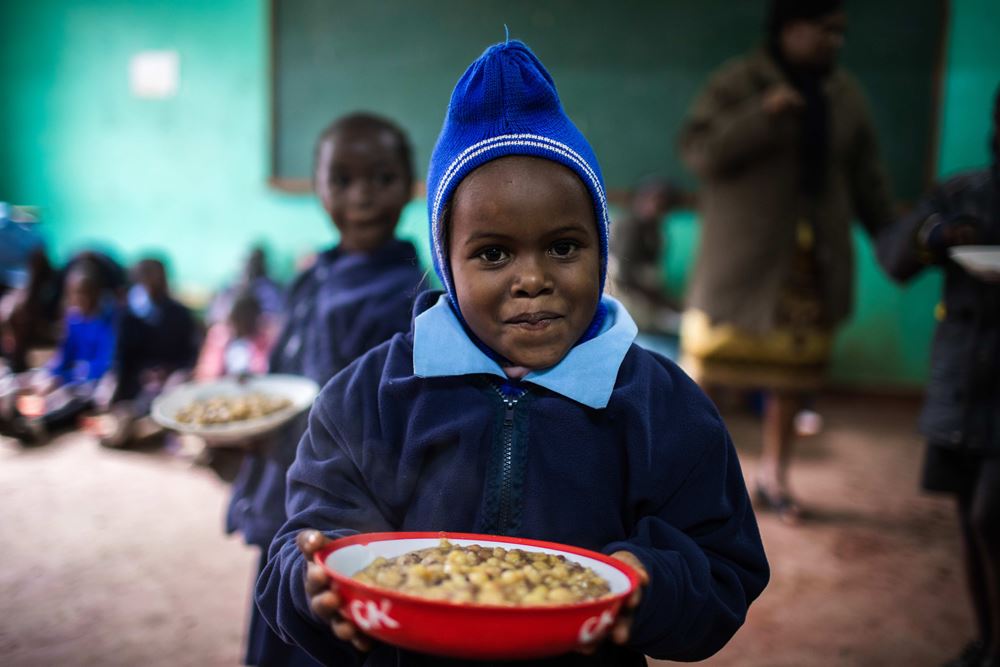 Ein kleines Kind hält sein Essen in einer Schüssel in der Hand. Foto: Lars Heidrich