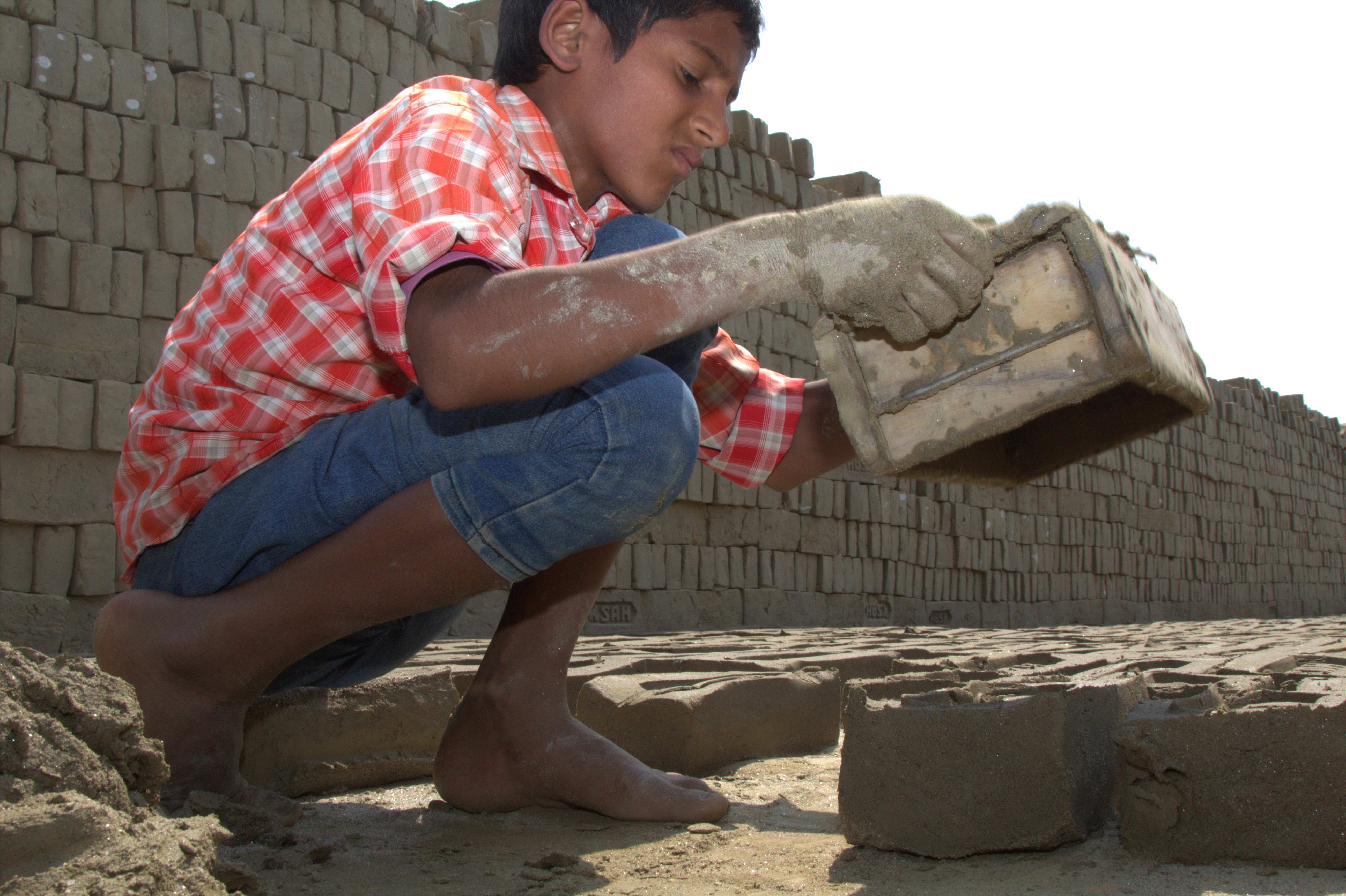 Ein Junge stellt Ziegelsteine her Ein Junge stellt Ziegelsteine her