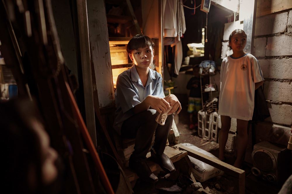 Ein Junge sitzt auf den Treppenstufen einer engen Wohnung in einem Slum in Manila, im Hintergrund lehnt ein Mädchen an der Wand. (Quelle Jakob Studnar)