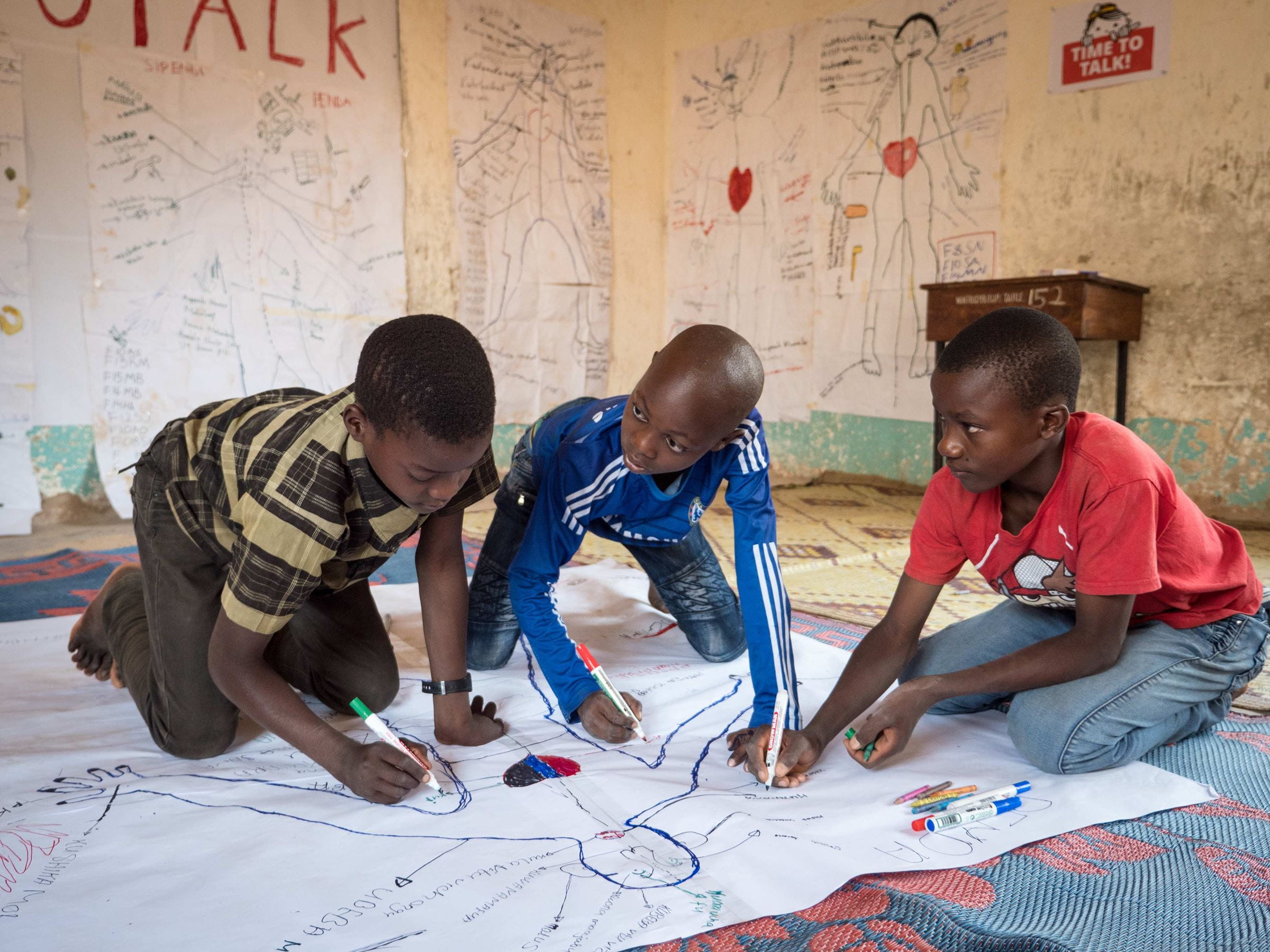 3 Jungs malen auf großem Papier für time to talk Kampagne (Quelle: Kindernothilfe)