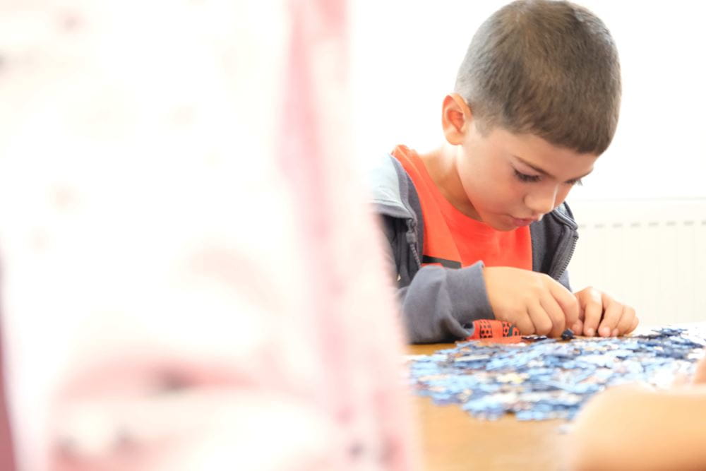 Ein Junge puzzelt am Tisch in einem rumänischen Projekt, Foto: Angelika Böhling