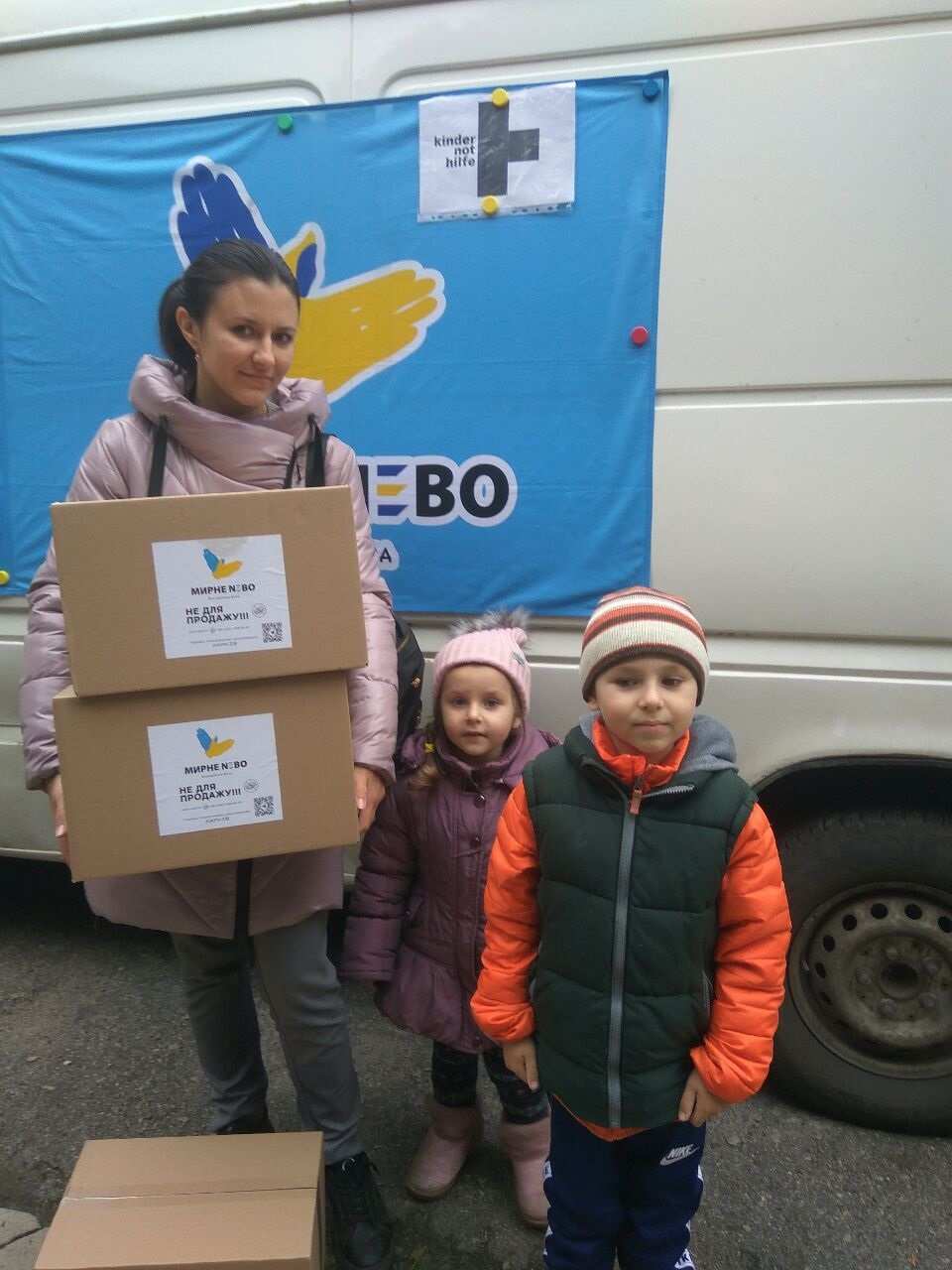Eine Mutter aus der Ukraine erhält eine Nahrungsmittelbox für Kinder. (Quelle: Myrne Nebo)