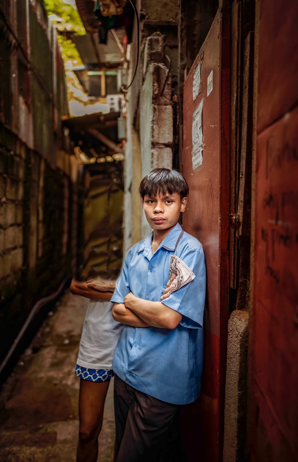 Ein Junge steht in einem Slum in Manila an eine Mauer gelehnt und schaut ernst in die Kamera (Quelle: Jakob Studnar) Platzhalterbild