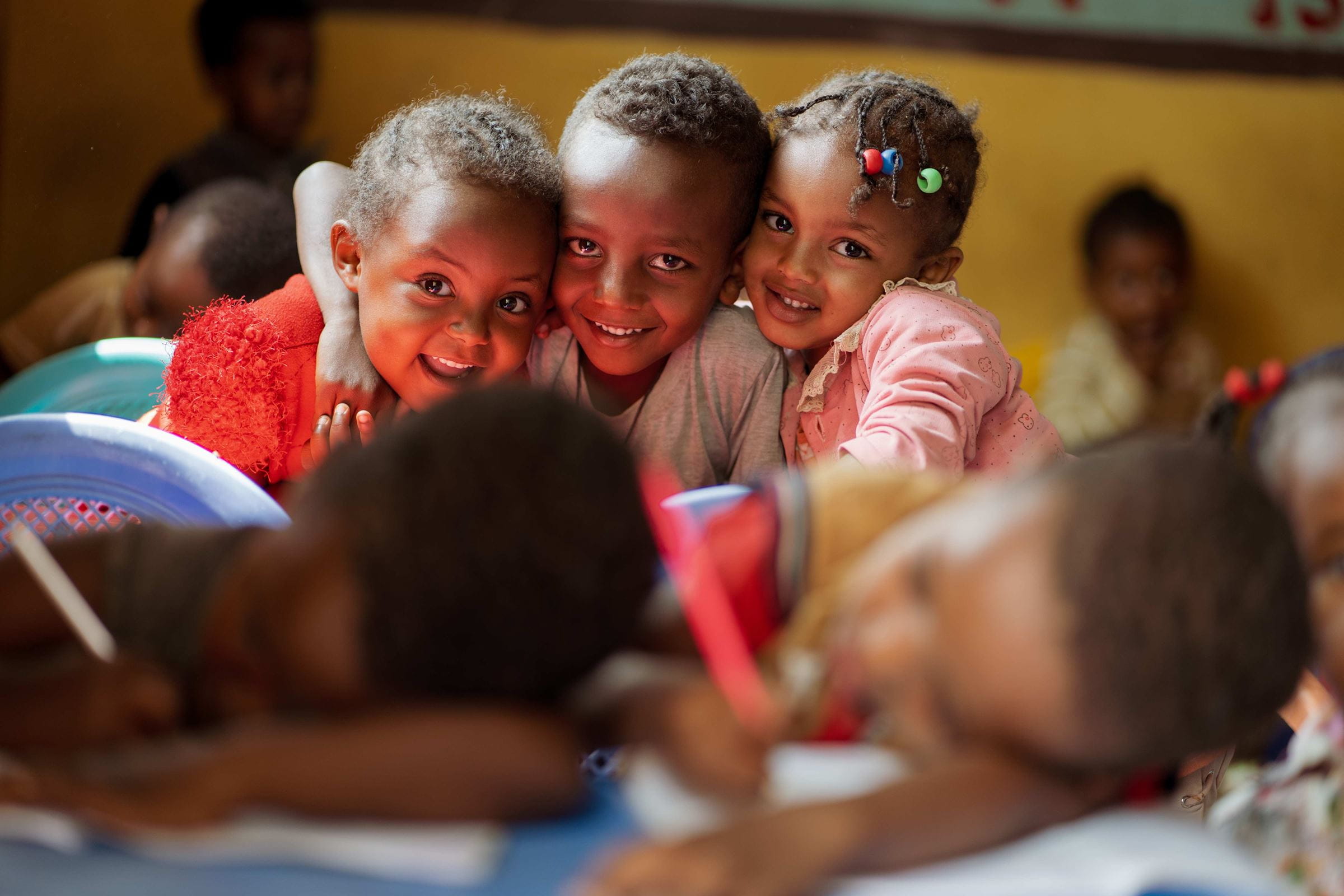Drei Kinder in Äthiopien stehen Arm in Arm und lachen. (Quelle: Jakob Studnar)
