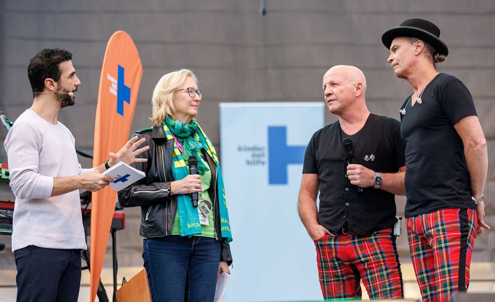 Moderator Daniele Rizzo und Kindernothilfe-Vorstandsvorsitzende Katrin Weidemann mit Brings-Mitgliedern im Gespräch auf der Bühne beim Kirchentag, Foto: Daniel Karmann/Kindernothilfe Moderator Daniele Rizzo und Kindernothilfe-Vorstandsvorsitzende Katrin Weidemann mit Brings-Mitgliedern im Gespräch auf der Bühne beim Kirchentag, Foto: Daniel Karmann/Kindernothilfe