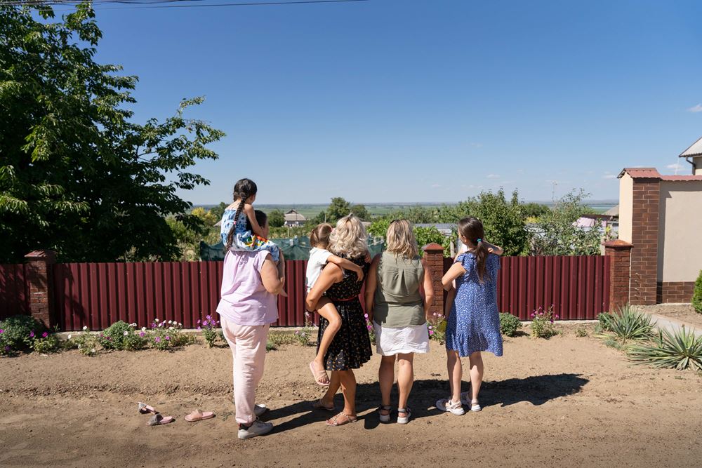 Blick über den Zaun in die Heimat: Frauen stehen mit ihren Kindern mit Rücken zur Kamera (Quelle: Kindernothilfe) Blick über den Zaun in die Heimat: Frauen stehen mit ihren Kindern mit Rücken zur Kamera (Quelle: Kindernothilfe)