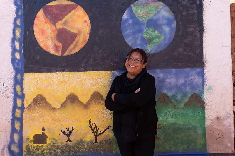 Bolivien: Lehrerin Celia vor Gemälden, die eine gesunde und eine überhitzte Erde zeigen (Quelle: Christian Nusch)