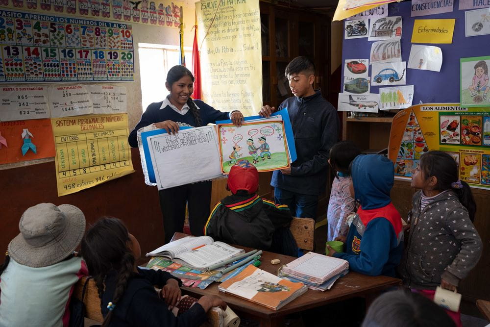 Zwei Jugendliche klären Grundschüler anhand eines großen Bilderbuchs über Umweltschutz auf (Quelle: Christian Nusch)