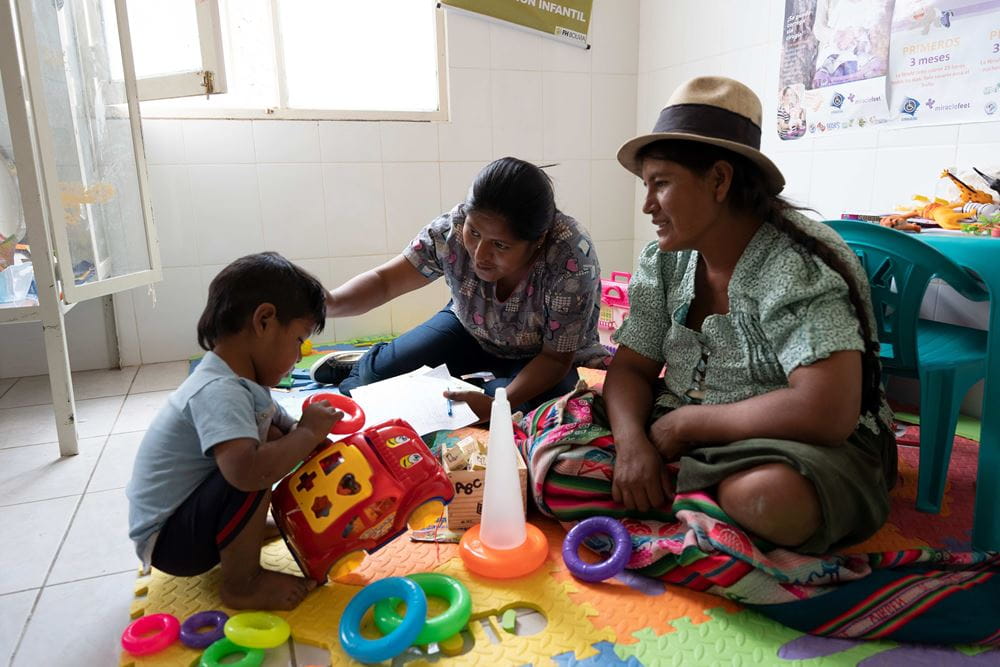 Bolivien, Gesundheitszentrum in Poroma: Ein kleiner Junge spielt, Mutter und Krankenschwester sitzen dabei (Quelle: Christian Nusch) Bolivien, Gesundheitszentrum in Poroma: Ein kleiner Junge spielt, Mutter und Krankenschwester sitzen dabei (Quelle: Christian Nusch)