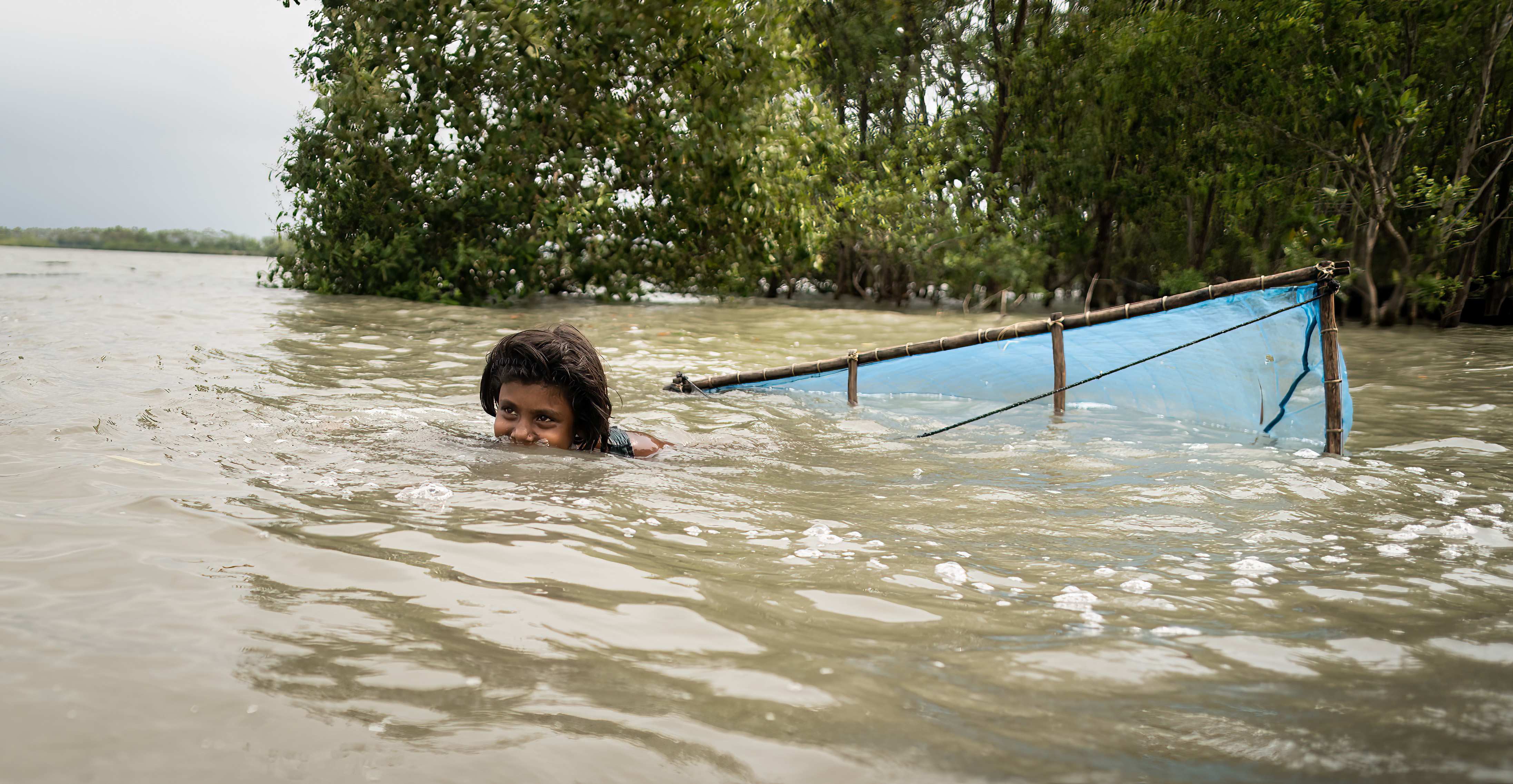 Bangladesch: Ein Mädchen schwimmt im Wasser und fischt Shrimps (Quelle: Lars Heidrich) Bangladesch: Ein Mädchen schwimmt im Wasser und fischt Shrimps (Quelle: Lars Heidrich)