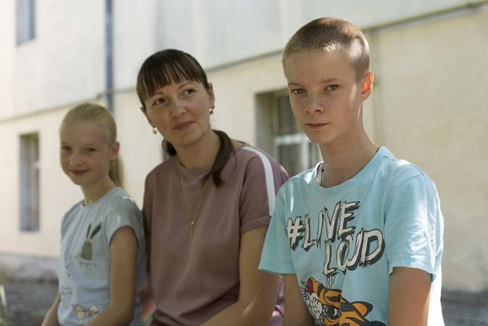 Alina sitzt mit ihrer Tochter Maria und Sohn Artem vor dem Schutzzentrum in Rumänien, in dem die Familie auf der Flucht vor dem Krieg in der Ukraine eine Bleibe gefunden hat (Quelle: Christian Nusch)