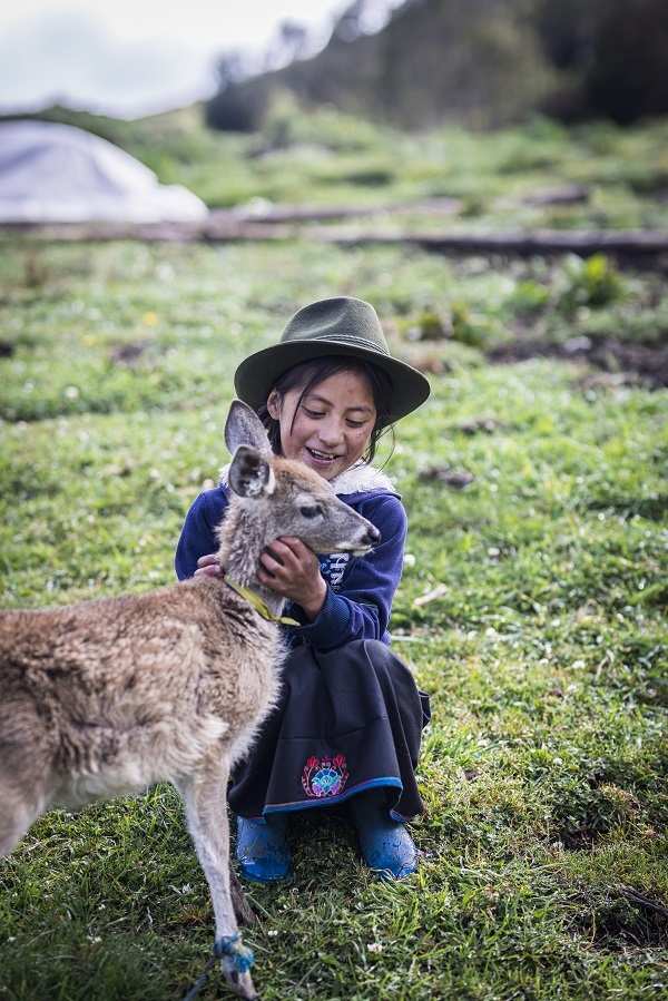 Ein Mädchen umarmt ein Reh auf einer Wiese (Quelle: Martin Bondzio)