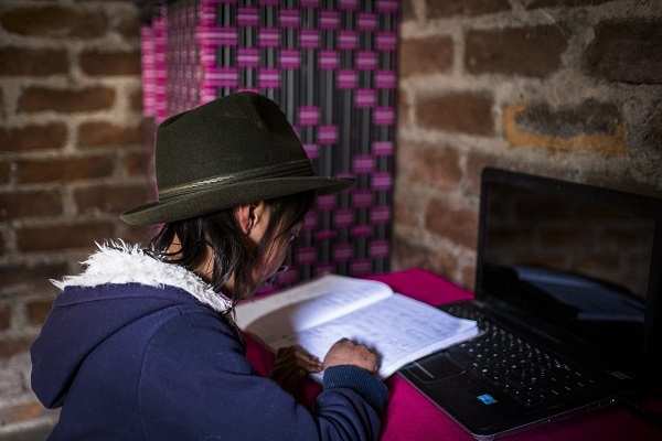 Ein Mädchen sitzt an eine, Schreibtisch mit Heft und Laptop (Quelle: Martin Bondzio)