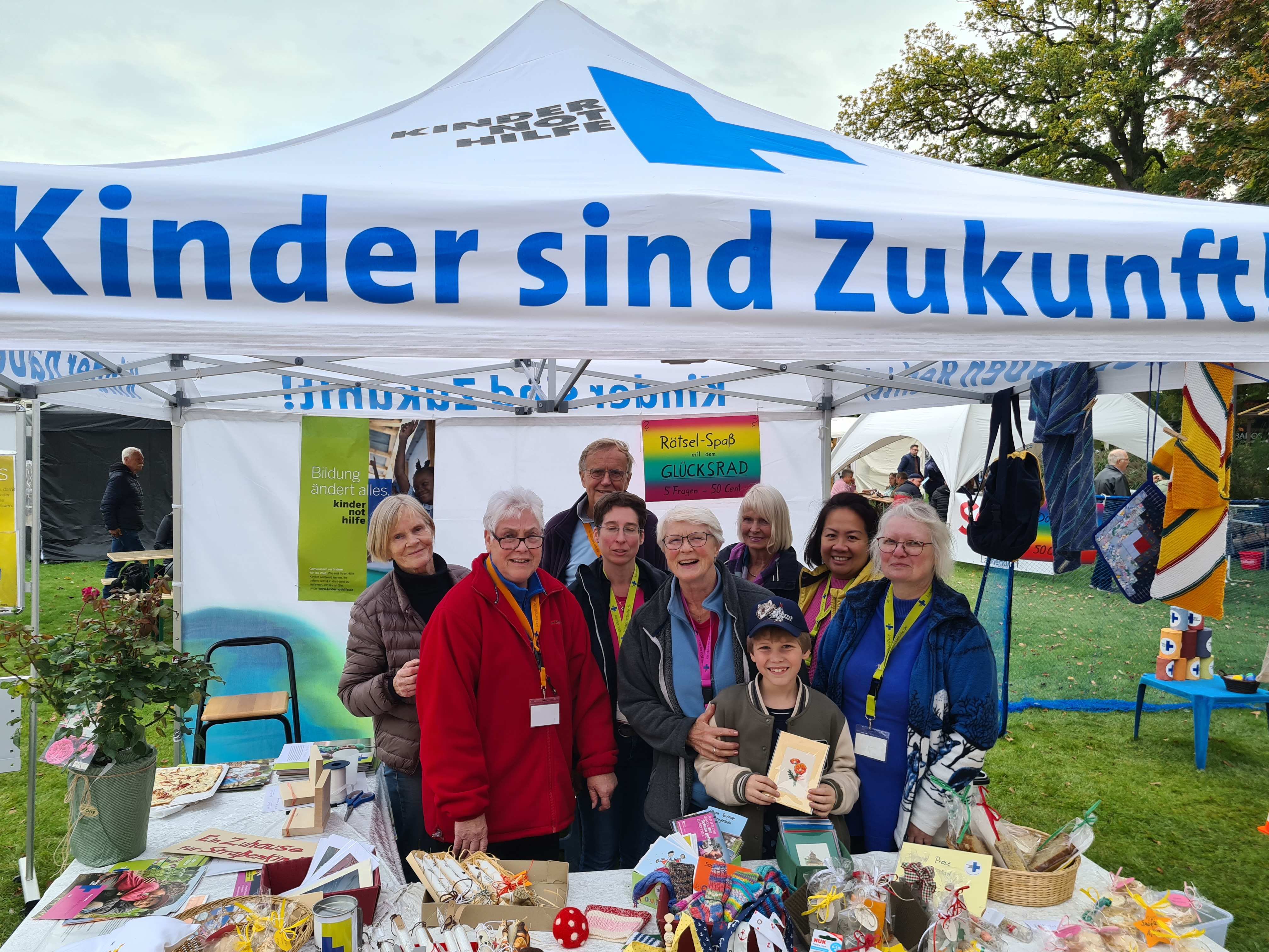Lachendorf: Infostand des Arbeitskreises, der sich zu einem Gruppenfoto im Kindernothilfe-Pavillon versammelt hat (Quelle: Christopher Vent).