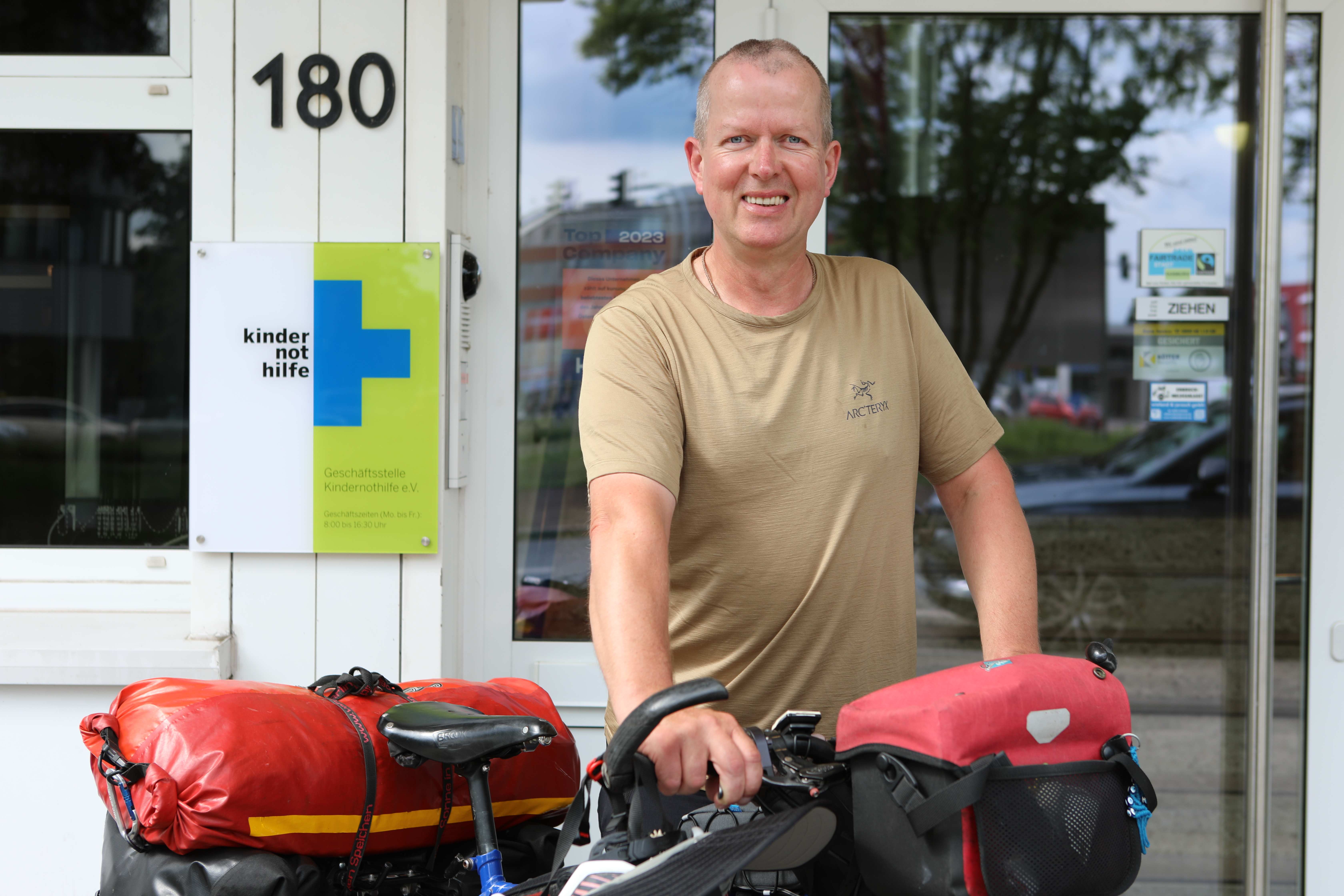 Christian Jung aus Berlin mit seinem Fahrrad vor dem Eingang zur Kindernothilfe (Quelle: Katharina Draub)