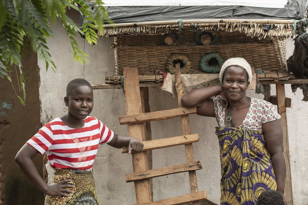 Blaze und ihre Mutter Mevis lehnen an einer Leiter vor ihrer Hütte in Malawi und lachen in die Kamera (Quelle: Christian Nusch) Platzhalterbild