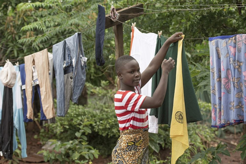 Ein  Mädchen hängt vor dem Haus ihrer Mutter in Malawi Wäsche zum Trocknen auf (Quelle: Christian Nusch) Platzhalterbild