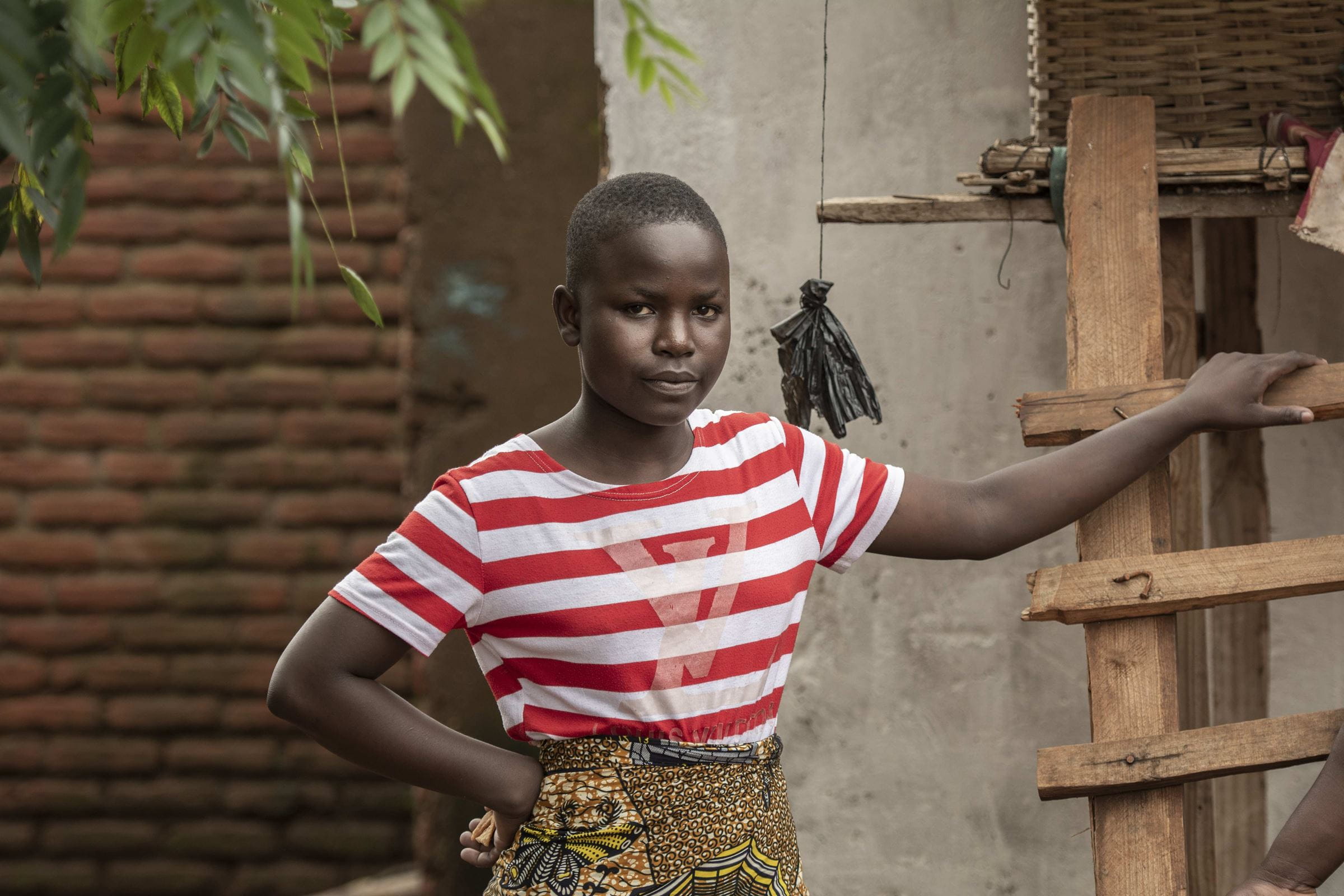 Ein Mädchen steht an eine Leiter gelehnt vor einem Haus in ihrer Heimat Malawi und schaut in die Kamera (Quelle: Christian Nusch)