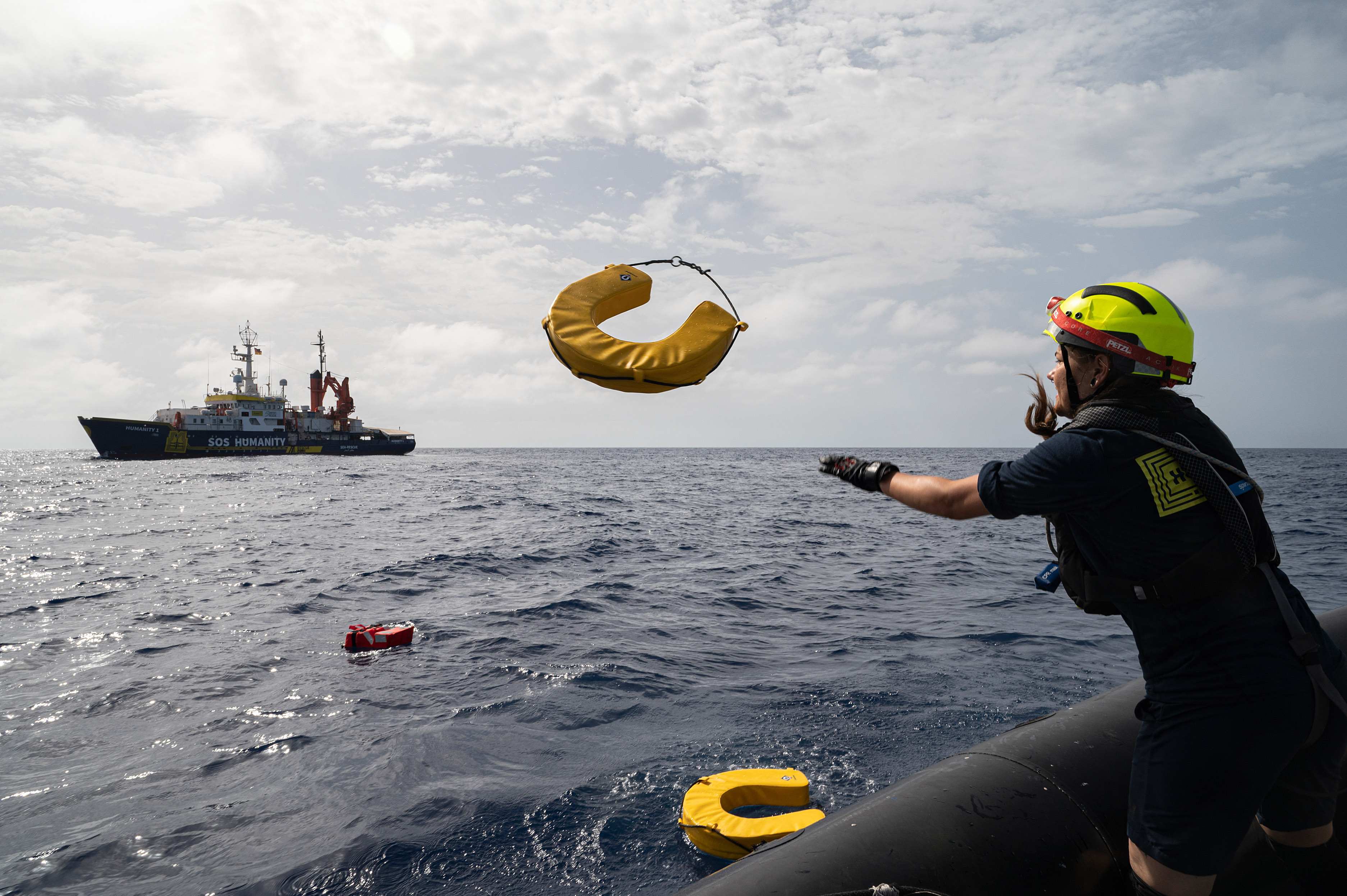 Eine Frau wirft einem Ertrinkenden einen Rettungsring zu (Quelle: Arez Ghaderi/SOS Humanity)