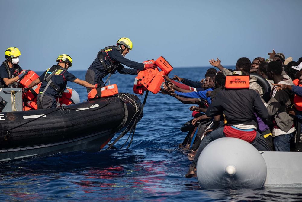 Ein Rettungsboot reicht Menschen auf einem anderen Boot Rettungswesten (Quelle: Max Cavallari/SOS Humanity)